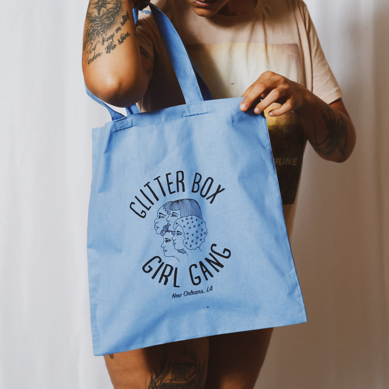 Glitter Box Girl Gang Tote Bag in Blue modeled by a person peeking into the bag. 