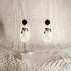 black and white Studio Joy earrings with a woman dressed up in a white dress and wearing a black hat